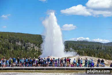 Tourists watching Old Faithful erupting